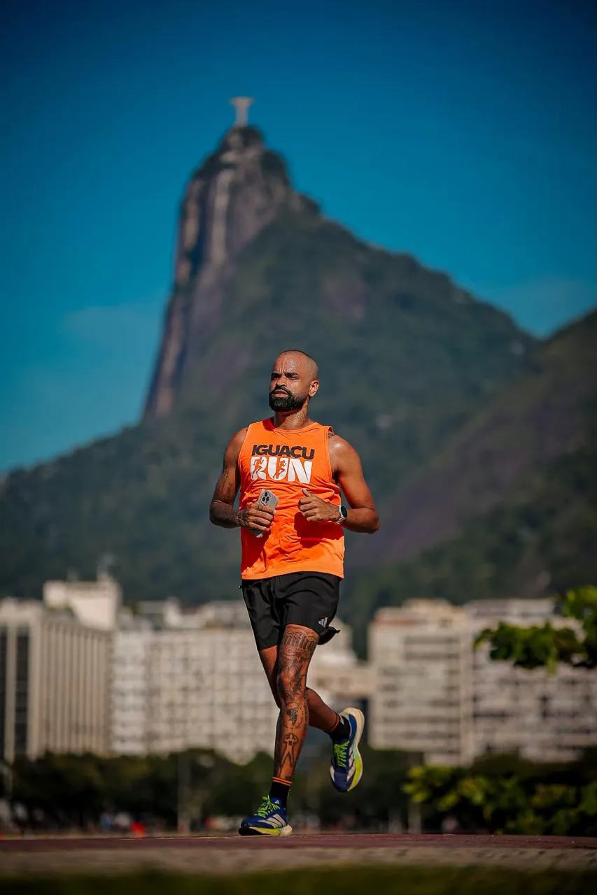 Rogério correndo com a camiseta do Iguaçu Run, com o Cristo Redentor ao fundo